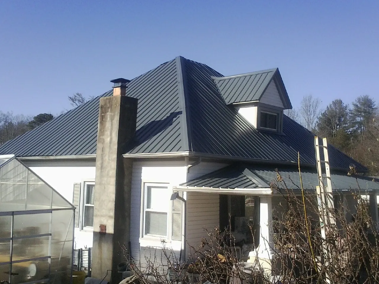 Dark blue standing seam metal roof on a white farmhouse with dormer — Slate & Tile Roof Repair by Roofing Brothers in Yorktown
