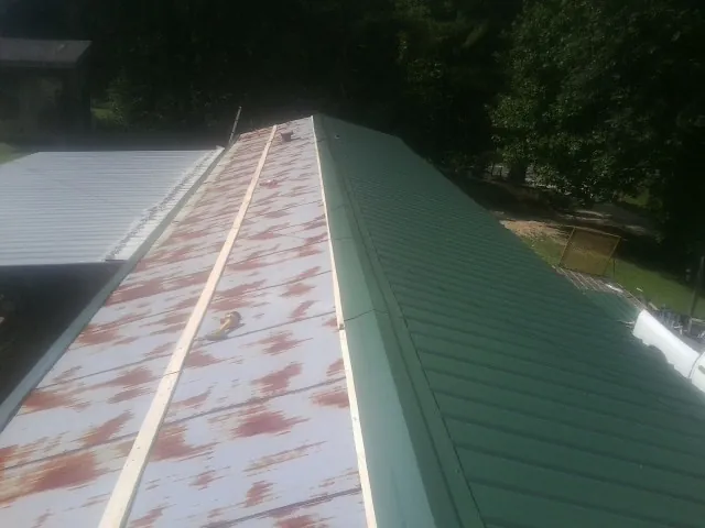 Old rusted panels beside newly installed green metal roofing — Wind Damage Roof Repair by Roofing Brothers in Yorktown