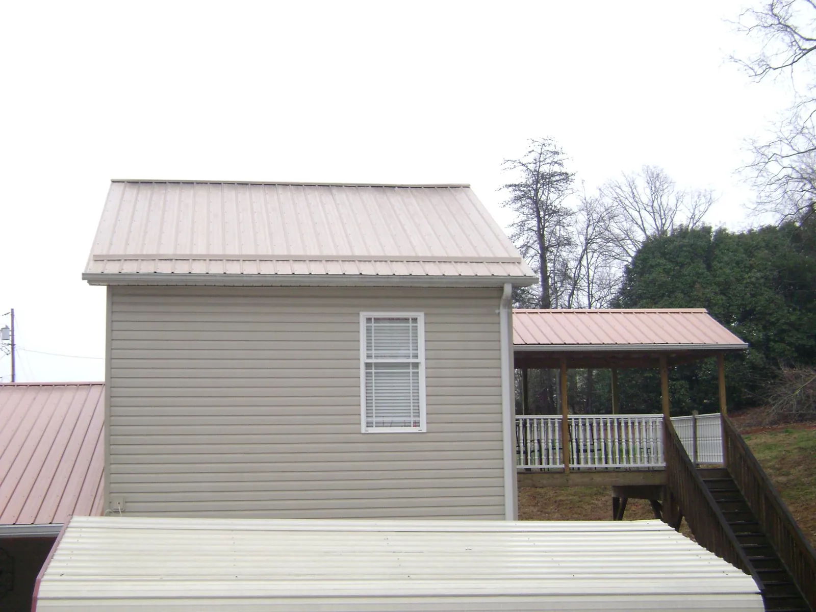 Tan metal roofs on a two story addition and attached porch, from a Roof Replacement job in Yorktown